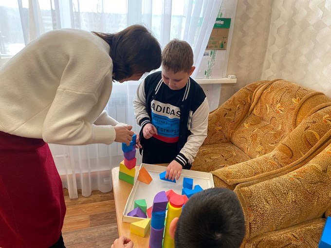 Под руководством психолога мальчик складывает кубики