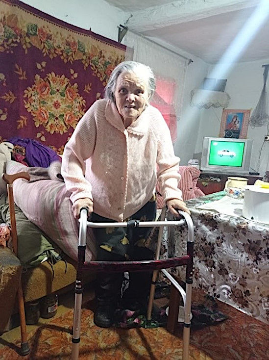Пожилая женщина держится за ходунки