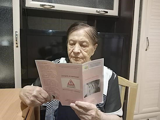 Пожилая женщина читает буклет