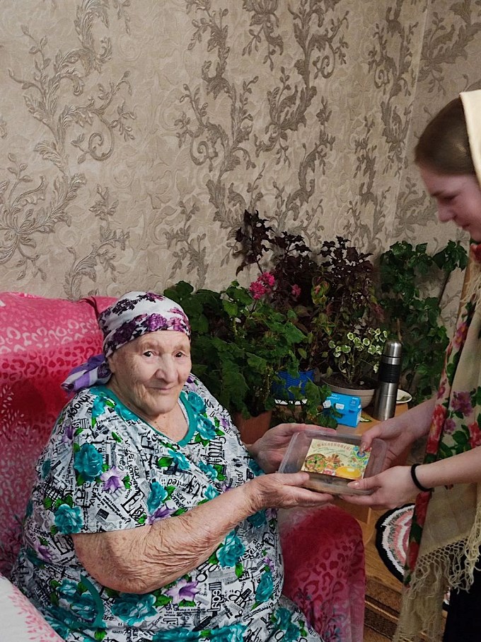 Школьница вручает блины пожилой женщине