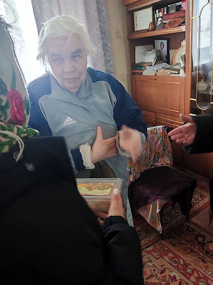 Школьница вручает блины пожилой женщине