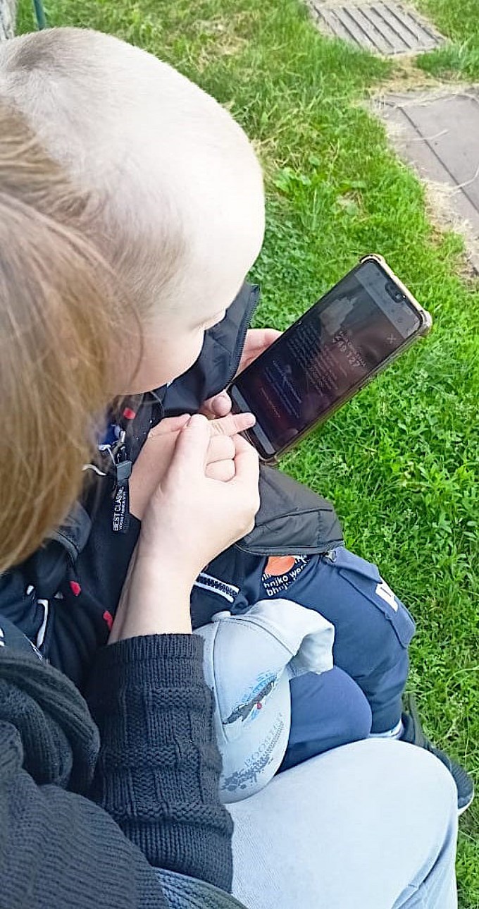 Специалист показывает мальчику как зажечь виртуальную свечу на смартфоне