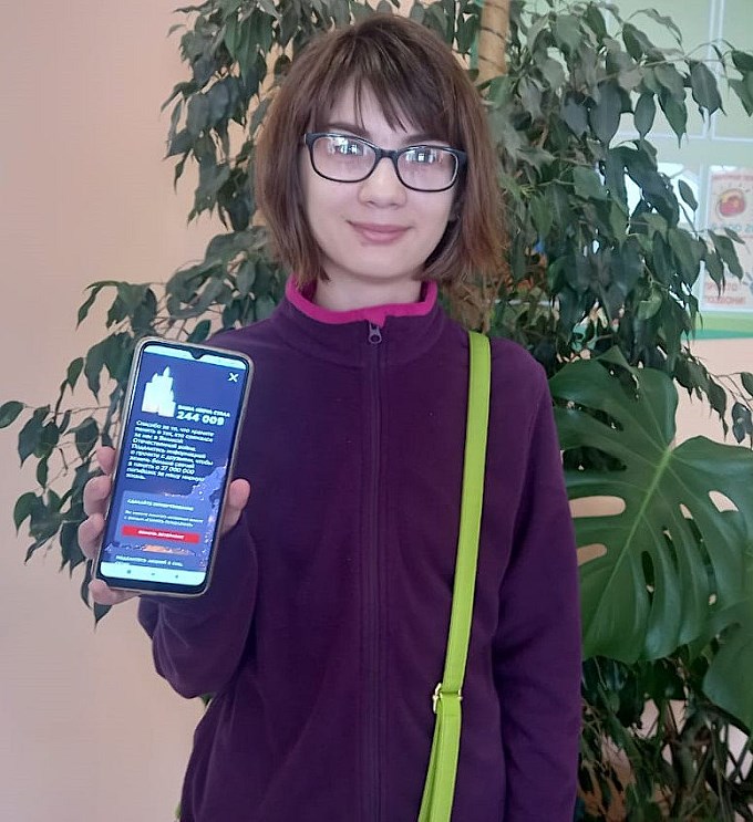 Девочка показывает на смартфоне зажжённую ею виртуальную свечу
