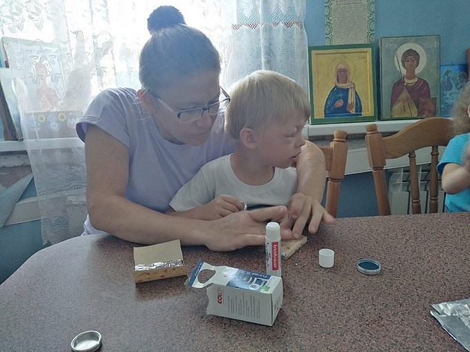 Мама помогает мальчику упаковать готовое мыло