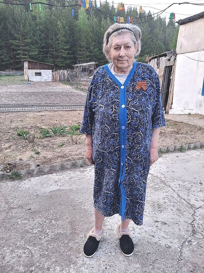Пожилая женщина с повязанной Георгиевской ленточкой