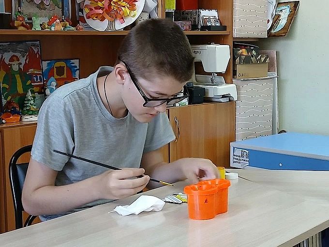 Мальчик раскрашивает бумажную фигурку самовара