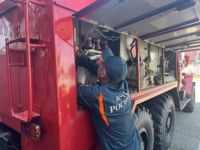 Сотрудник МЧС показывает детям устройство пожарного автомобиля