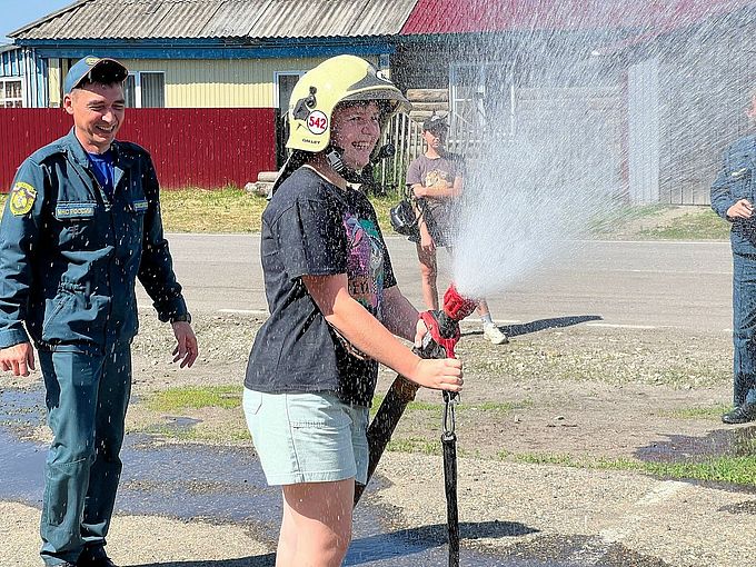 Девочка удерживает пожарный ствол под давлением