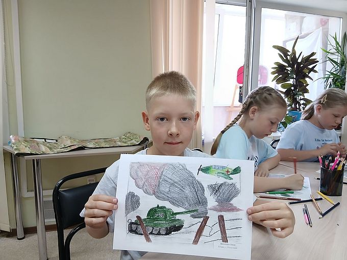 Мальчик показывает рисунок военного сражения