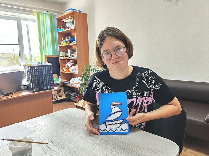 Девочка показывает аппликацию «Кораблик»