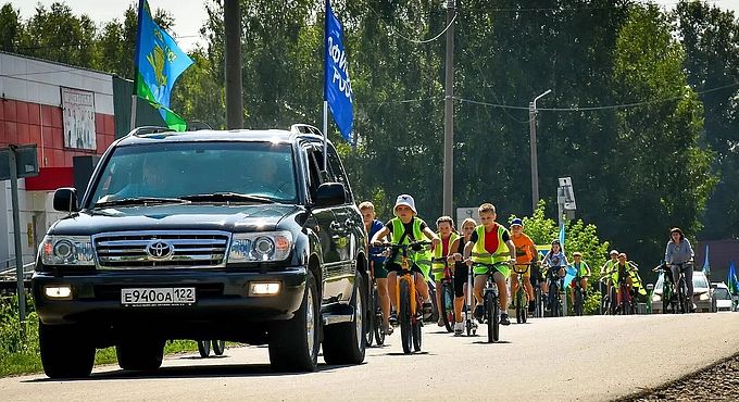 Дети на велосипедах едут вслед за автомобилем