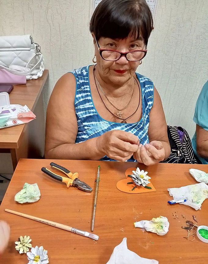 Пожилая женщина завершила создание аппликации «Сердечко с цветком»