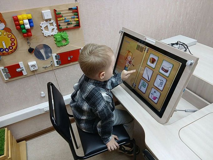 Мальчик выбирает на экране музыкальный инструмент