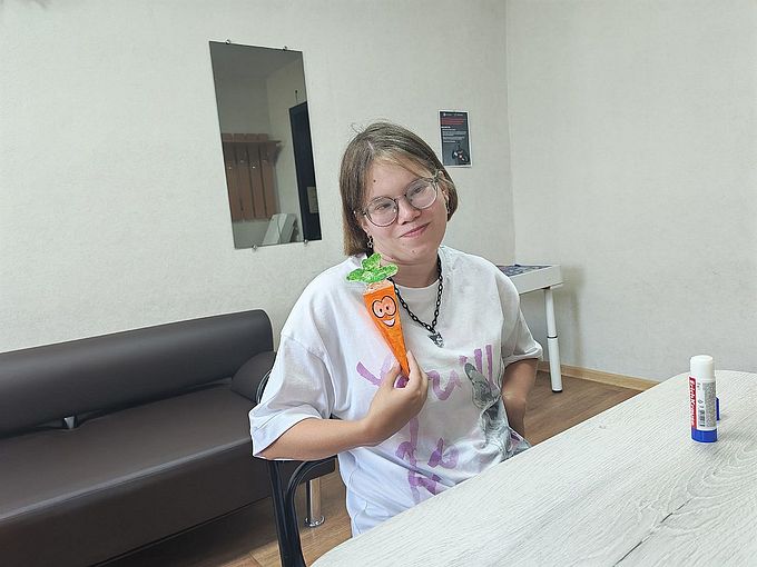 Девочка показывает созданную ею объёмную аппликацию моркови