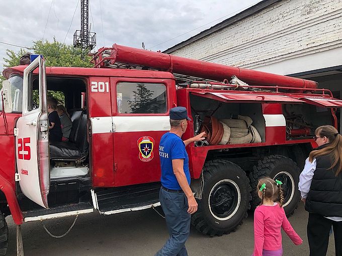 Пожарный показывает содержимое багажных отделений пожарного автомобиля