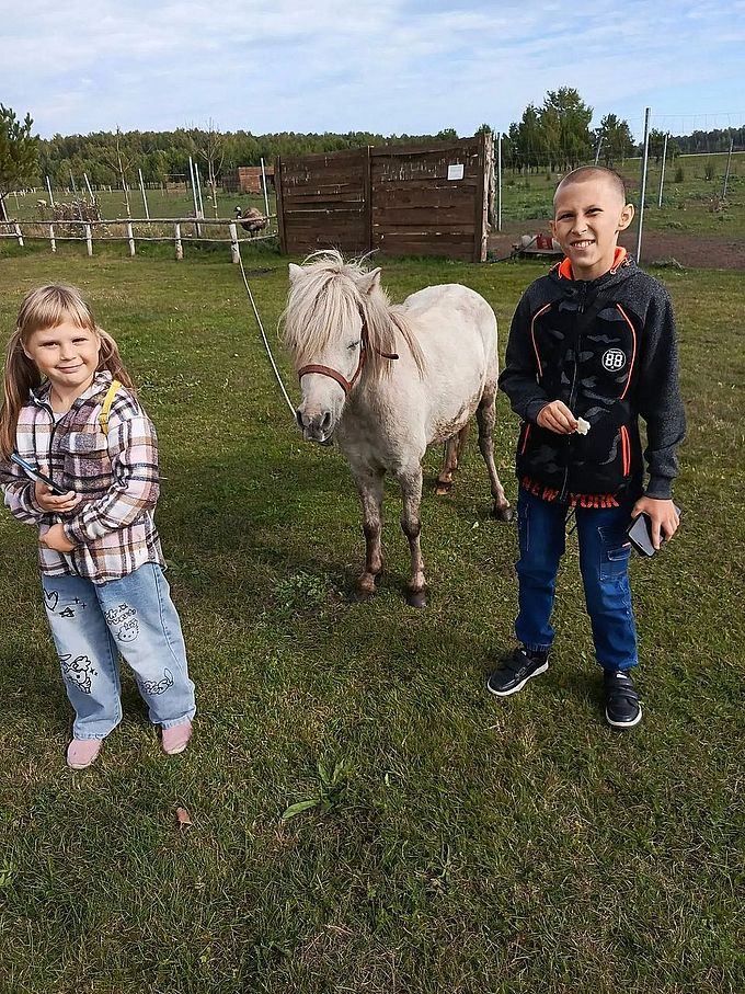 Девочка и мальчик рядом с белым пони