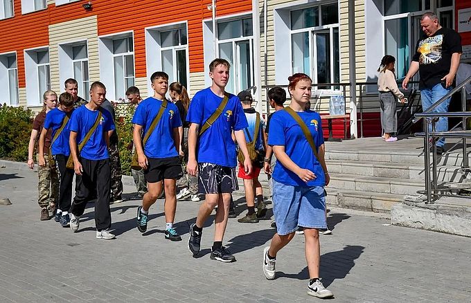 Команда ребят шагает перед крыльцом школы