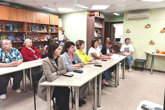 Сотрудники Комплексного центра слушают лектора, сидя за партами