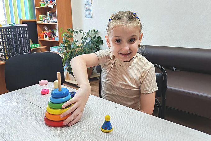 Девочка собирает цветную пирамидку