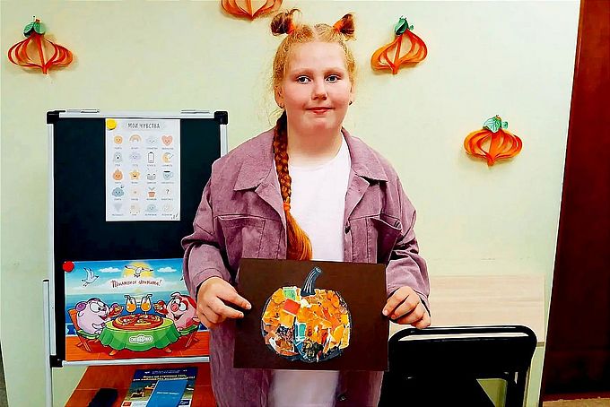 Девочка показывает созданный ею коллаж «Тыква»